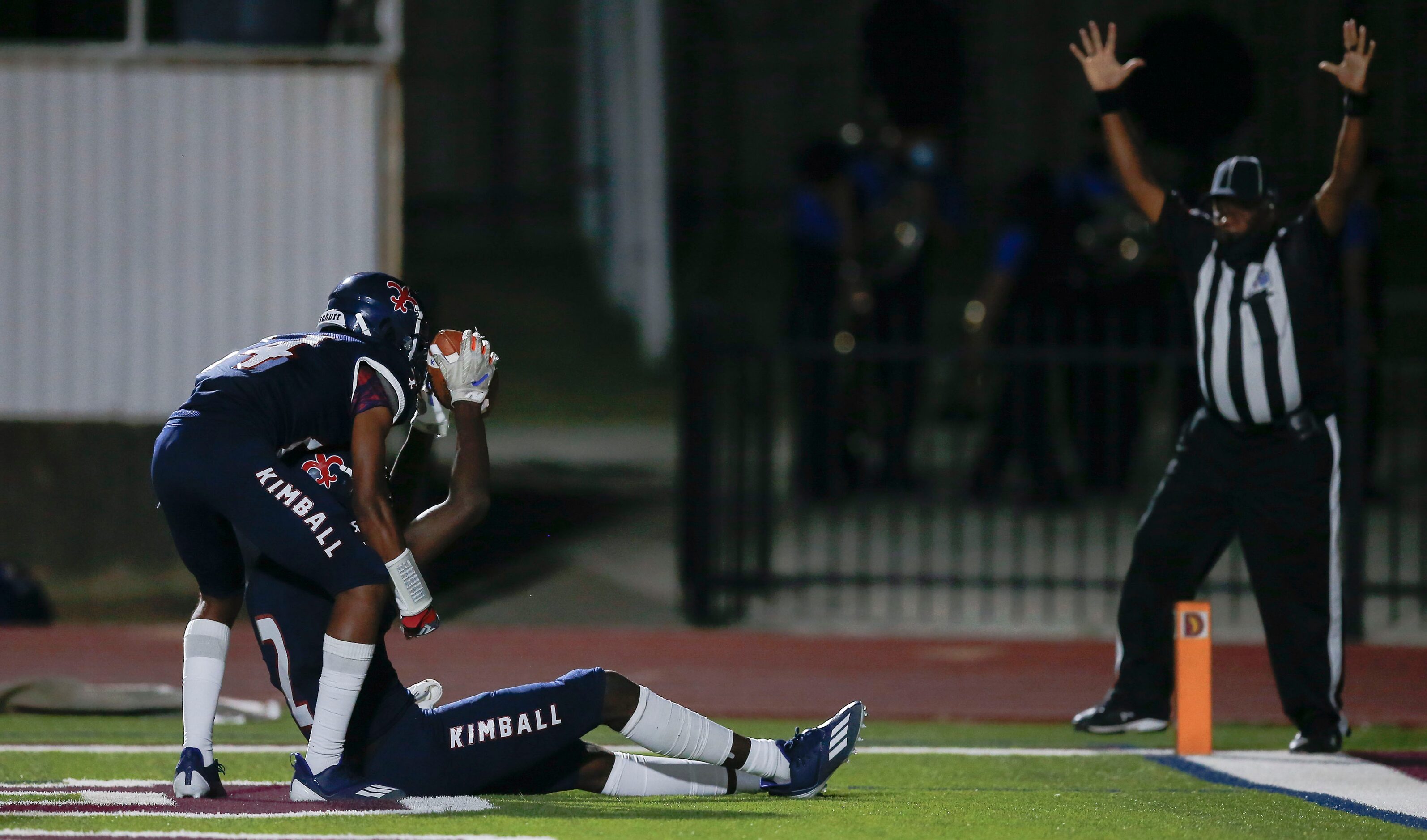 Kimball senior wide receiver Kyron Henderson (2) is helped to his feet by sophomore wide...