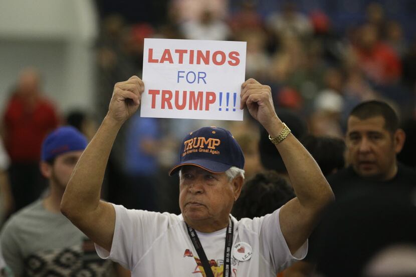A Hispanic man holds up a sign for Republican presidential candidate Donald Trump before the...