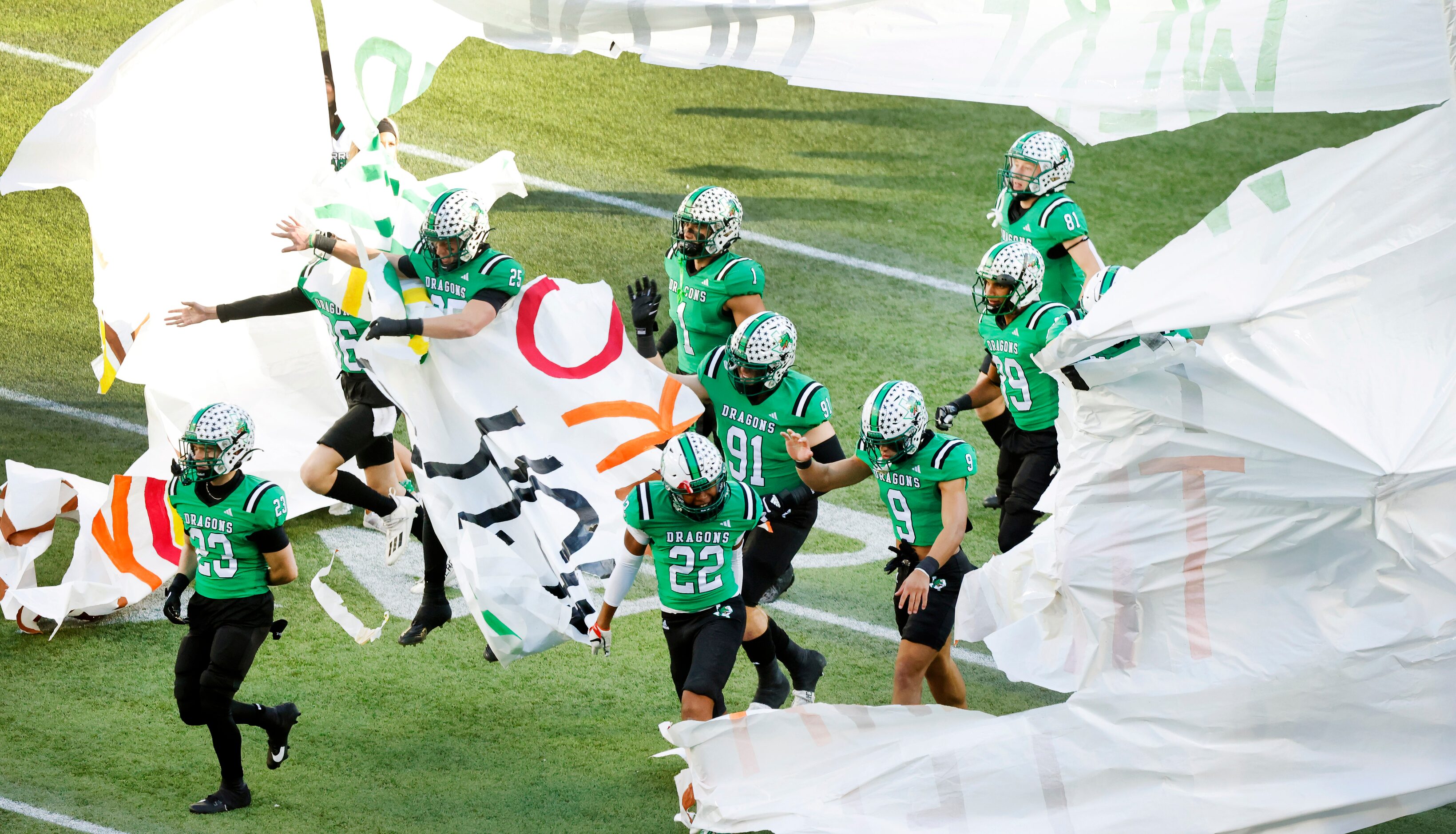 Southlake Carroll Dragons football players break through the cheerleader’s banner before...