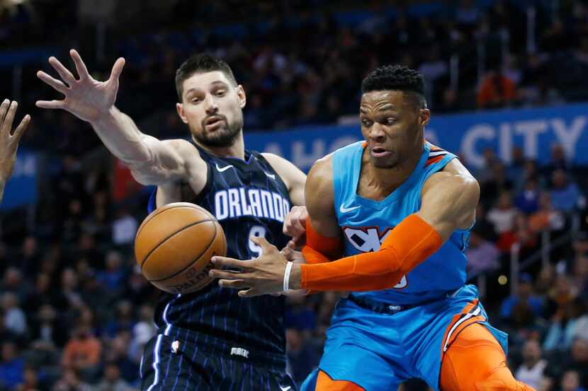 Oklahoma City Thunder guard Russell Westbrook, right, passes the ball in front ofOrlando...