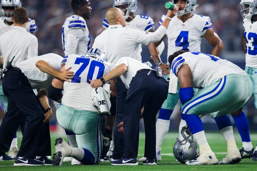 Cowboys guard Zack Martin (70) is checked on after suffering an injury during the first half...
