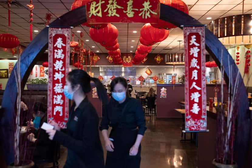 Employees wearing face masks walk towards the front to cater to customers inside Jeng Chi...
