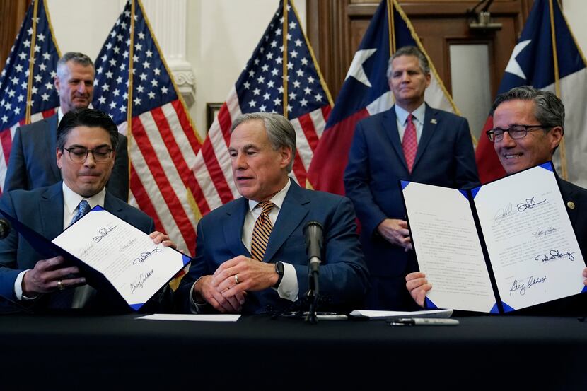 At Gov. Greg Abbott's signing ceremony of new electricity laws in 2021, Abbott (center) and...