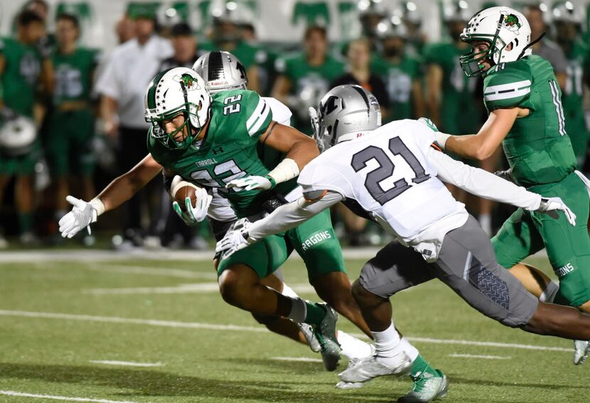 Southlake Carroll's Robert Barnes (22) is tackled by Arlington Martin's Tre Applon (21)...