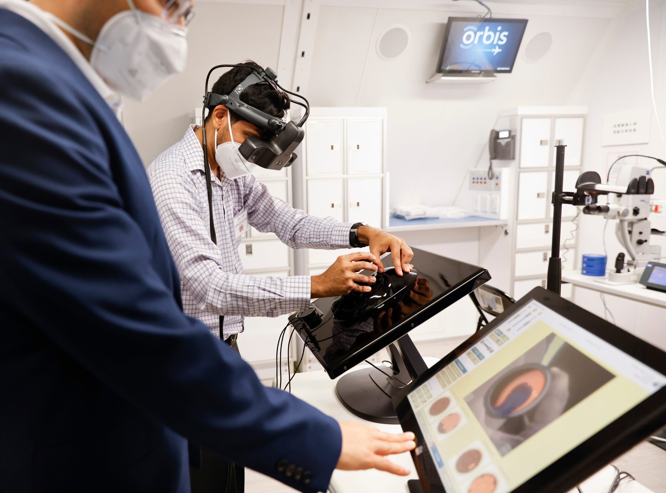 Orbis Flying Eye Hospital ophthalmologist Dr. Eduardo Mora, front, instructs resident Dr....