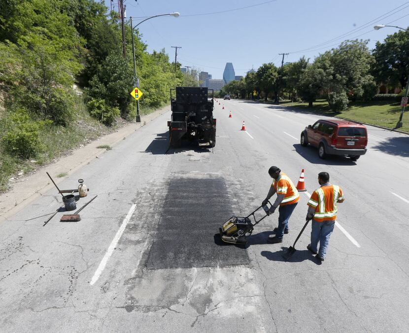 Dallas Street Services employees Gary Johnson, center, and Gary Langley, right, work to fix...