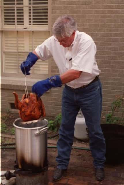 John Bass demonstrates taking the turkey out of the hot oil.