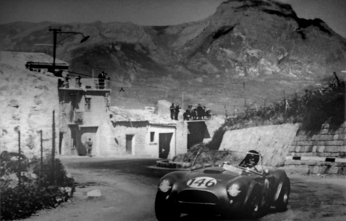 A copy of a photo of a Shelby Cobra in competition in Italy hangs  on the wall of the office...