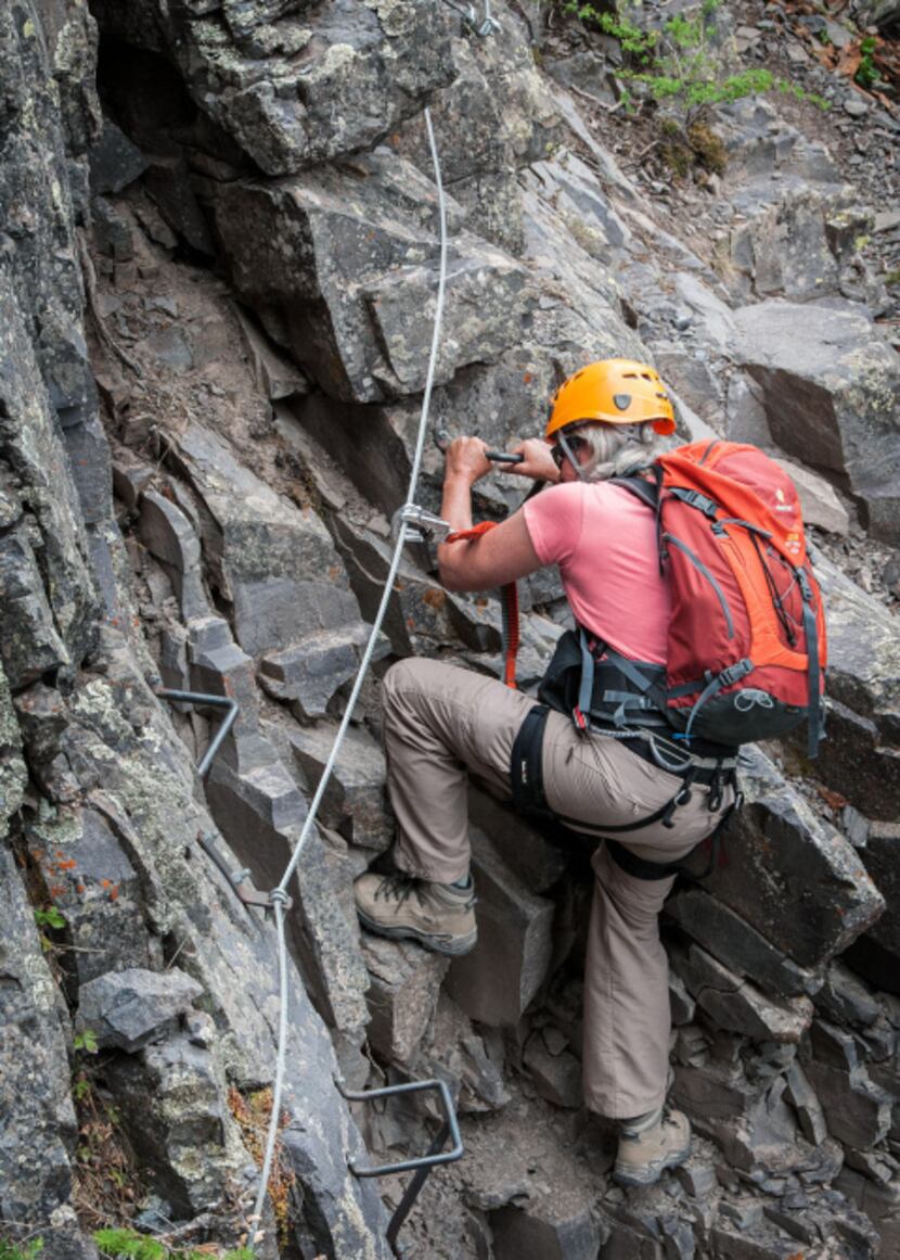 Dianne Leeth uses ladder rungs to work around an obstacle on Telluride's Via Ferrata.  While...