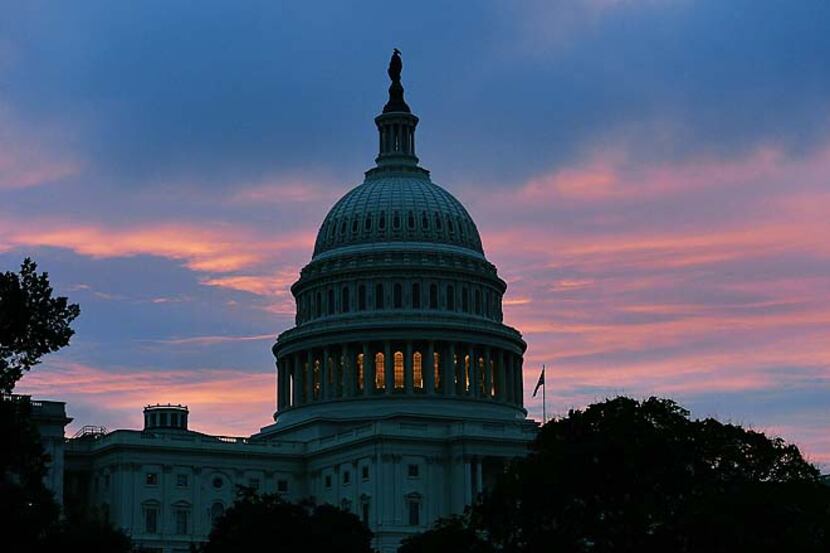 The sun rises behind the US Capitol building on Oct. 17, the morning after the House and the...