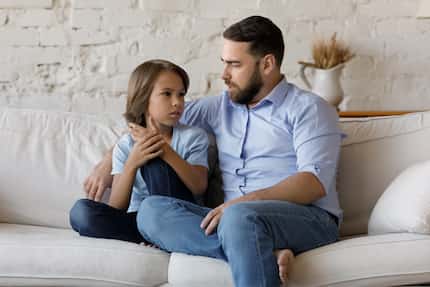 Padre e hijo hablan mientras están sentados en un sofá en casa.