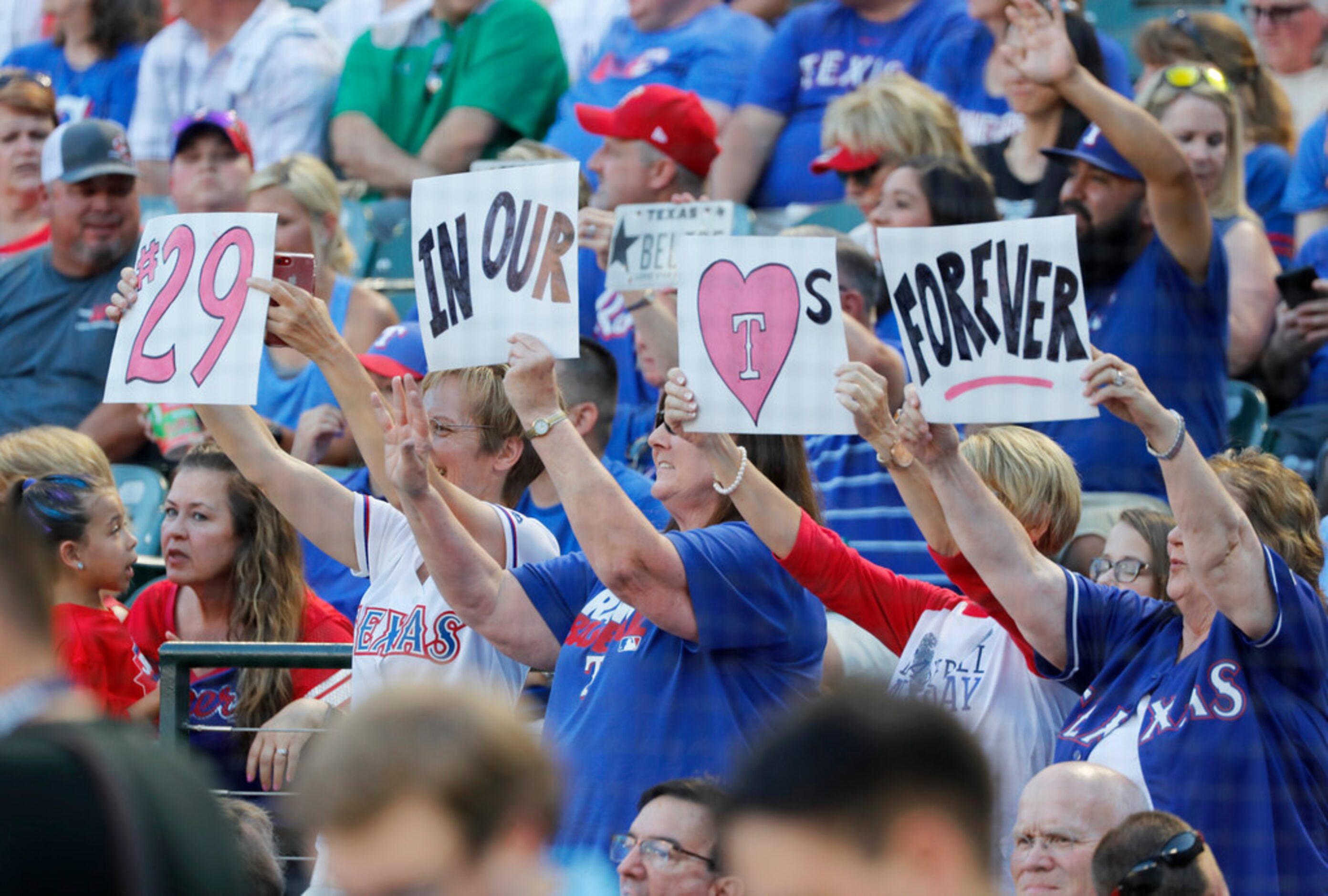 Fans hold up signs honoring former Texas Rangers player Adrian Beltre during a jersey...