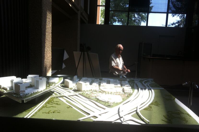 A man slows to look at miniature model of a mini city on the abandoned Texas Stadium site in...