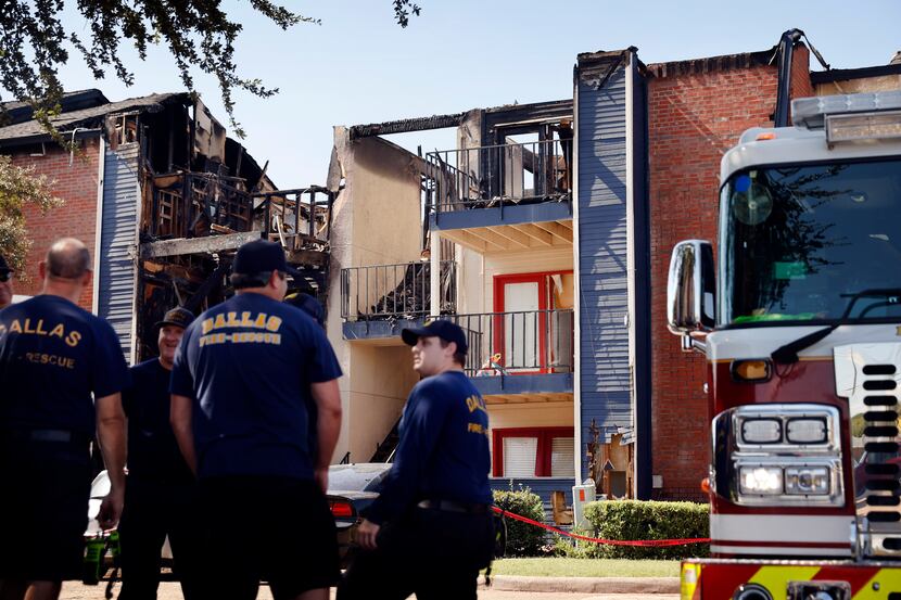 Dallas firefighters keep watch over the burned out, three-story apartment building at the...