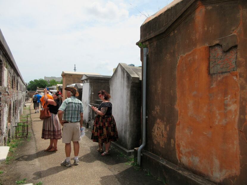 Tourists at St. Louis Cemetery No. 1 in New Orleans look at the cemetery's above-ground...