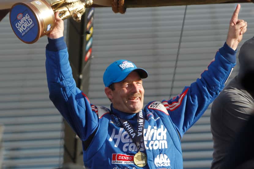 Pro Stock driver Greg Anderson hoists the first place trophy to the cheer of racing fans...