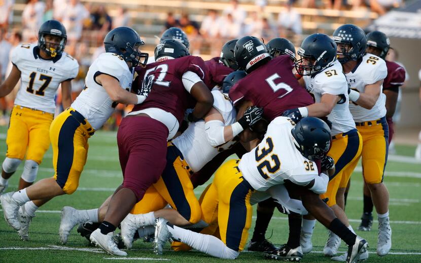 Highland Park defenders tackle Mansfield Timberview quarterback Jyron Russell (#5) during...