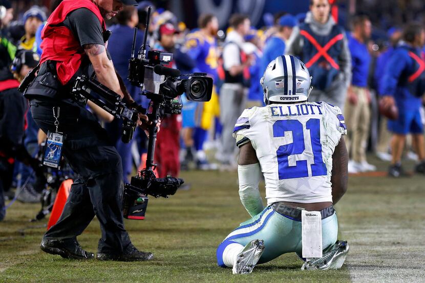Dallas Cowboys running back Ezekiel Elliott (21) kneels on the sideline after narrowly...