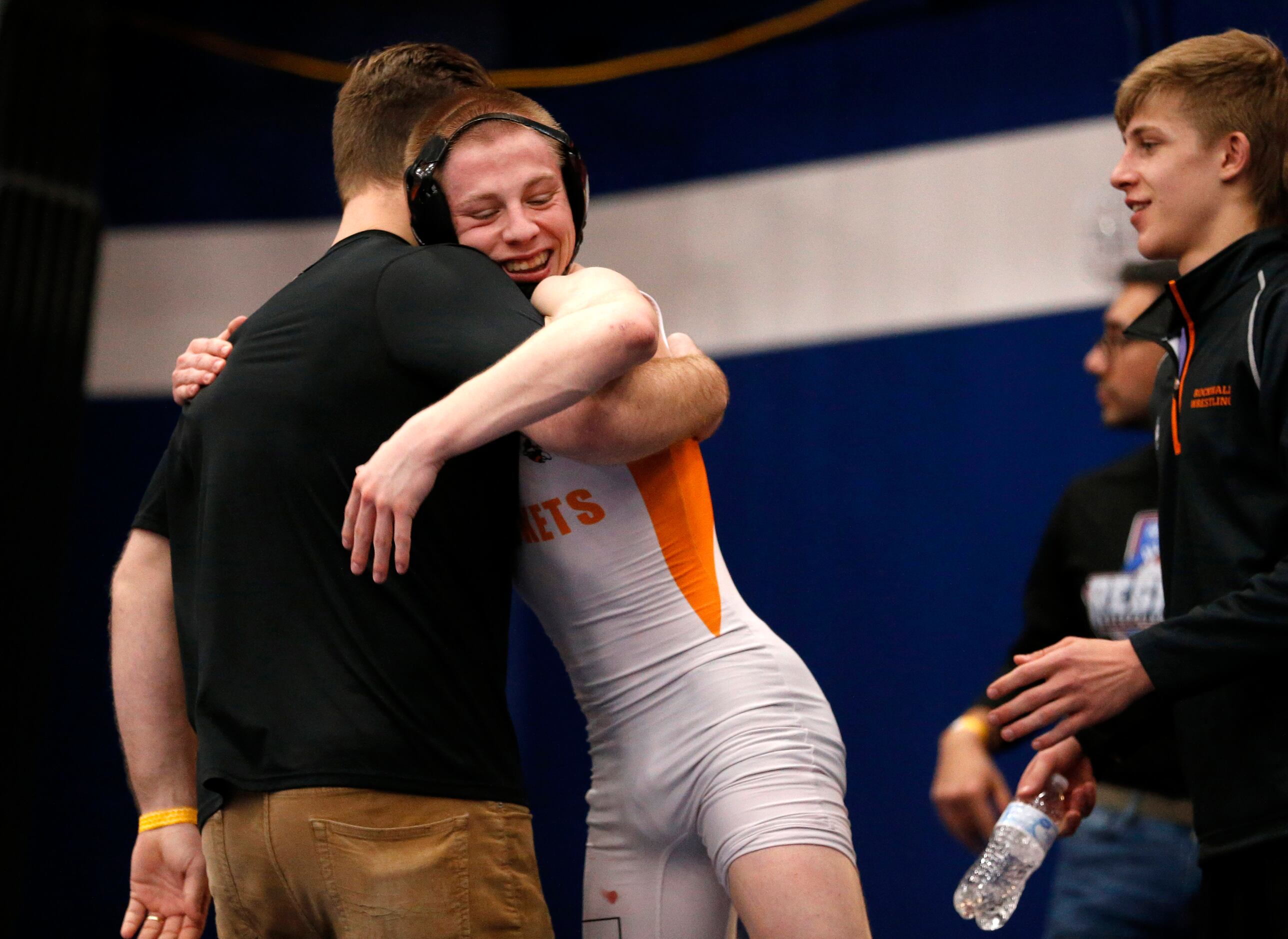 Rockwall High wrestler Hunter Males receives a hug from his coach Cody Johnston after...