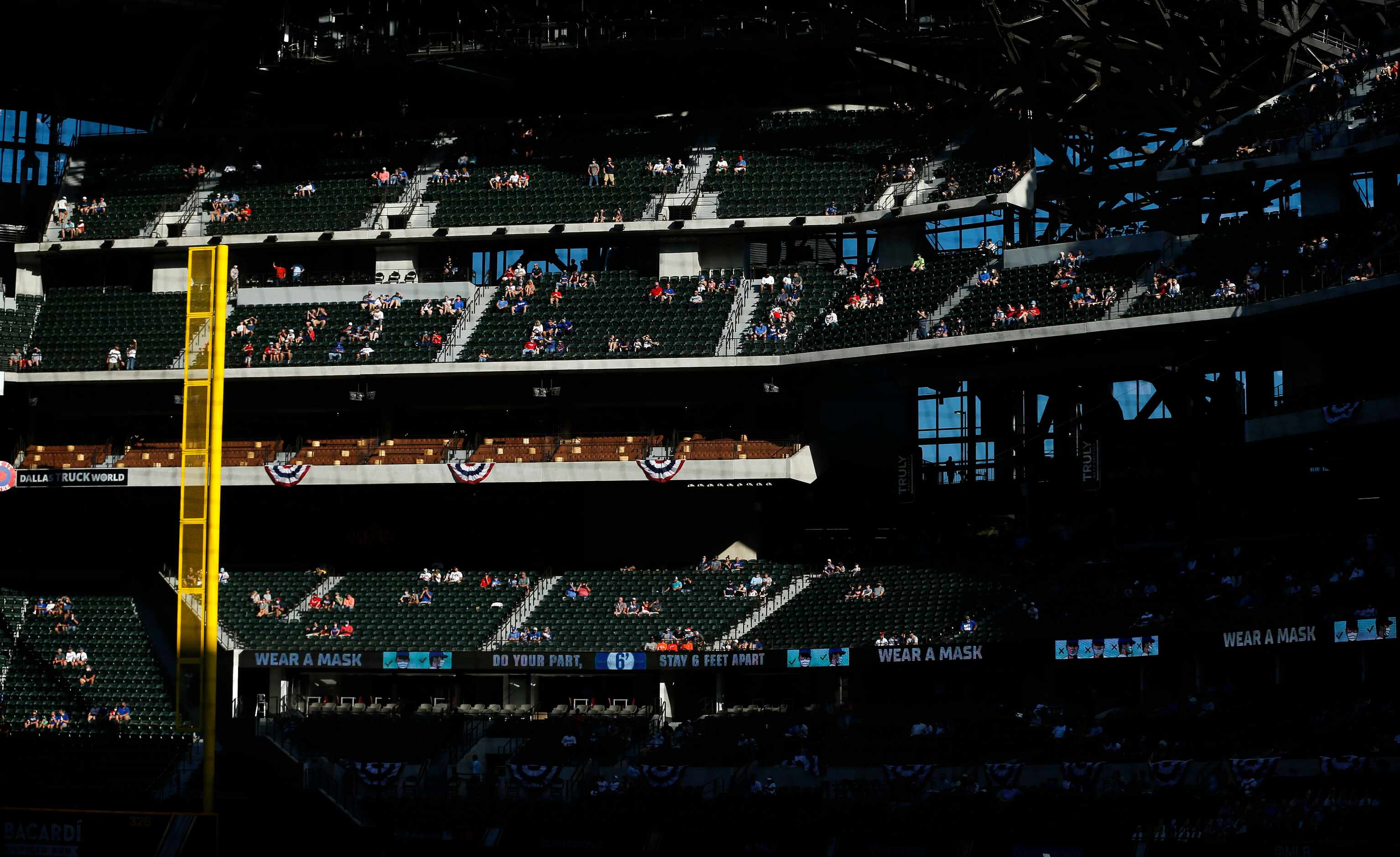 Sunlight pours through the open roof as socially-distanced fans watch the first inning in...