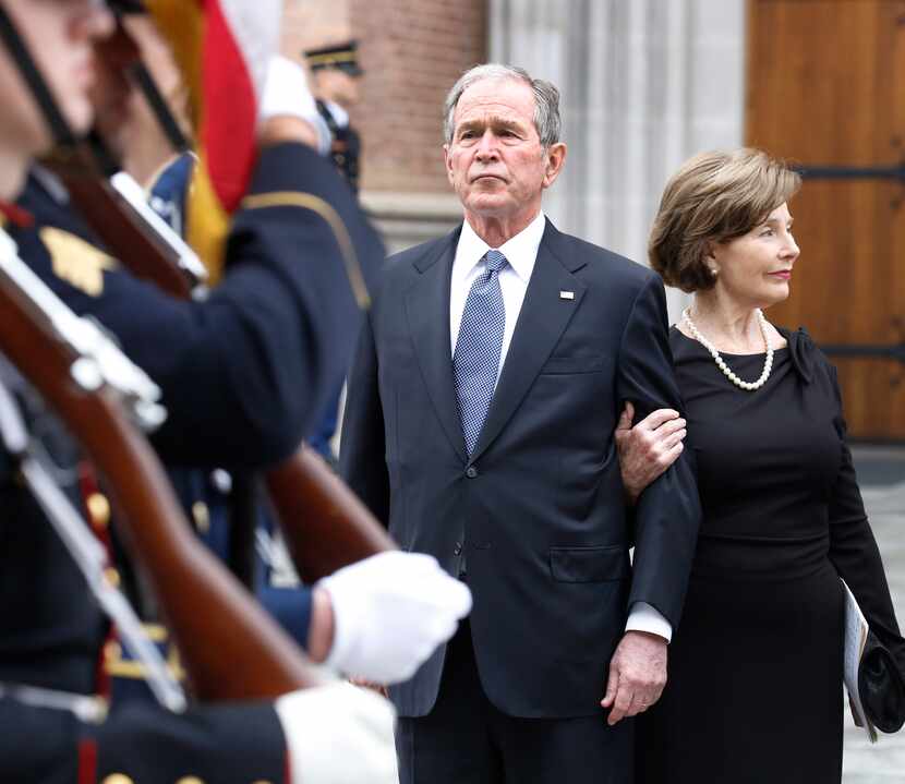 Former President George W. Bush and wife Laura Bush watch as the honor guard walks away at...