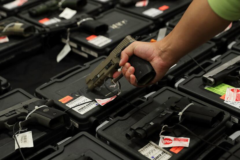 A potential buyer tries out a gun at a gun show in Virginia in 2016. Not all gun buyers...