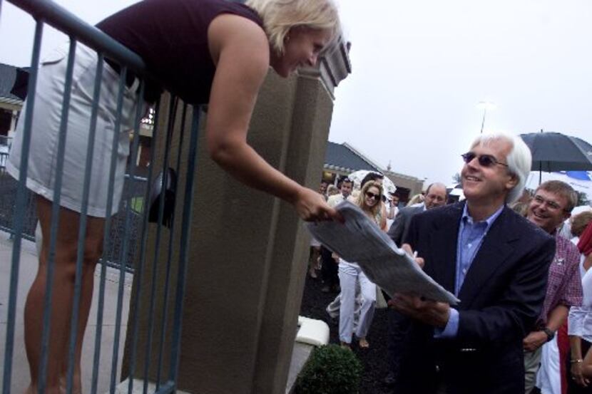  Trainer Bob Baffert signs autographs for an unidentified fan before the Lone Star Handicap...