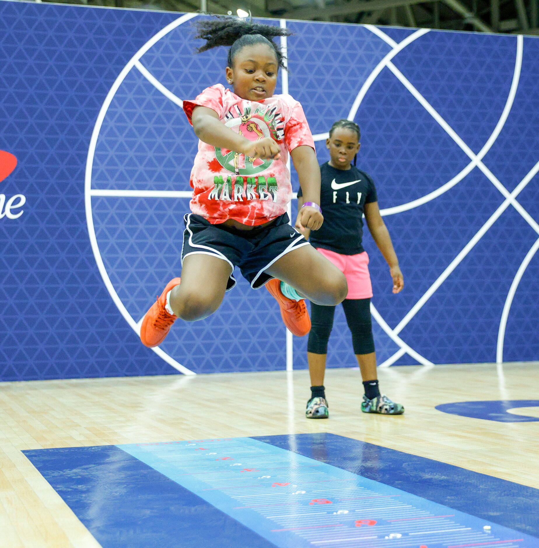 Danaae Wallace, 9, leaps to measure her broad jump during a skills challenge at the NCAA...