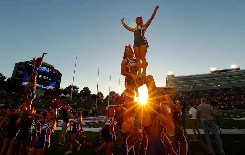 The sun sets behind SMU cheerleaders as they prepare for kickoff against the Houston Cougars...
