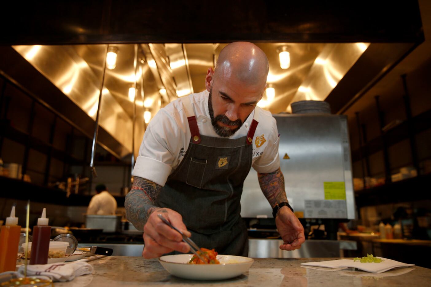 Chef James Robert works on a dish of pescavore grits at Fixe in Fort Worth, Texas,...