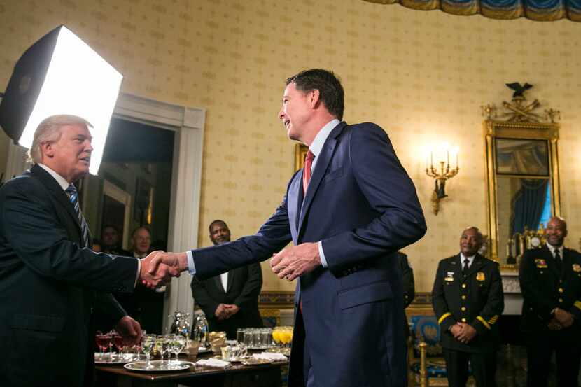 FBI Director James Comey crosses the room to shake hands after being recognized by President...