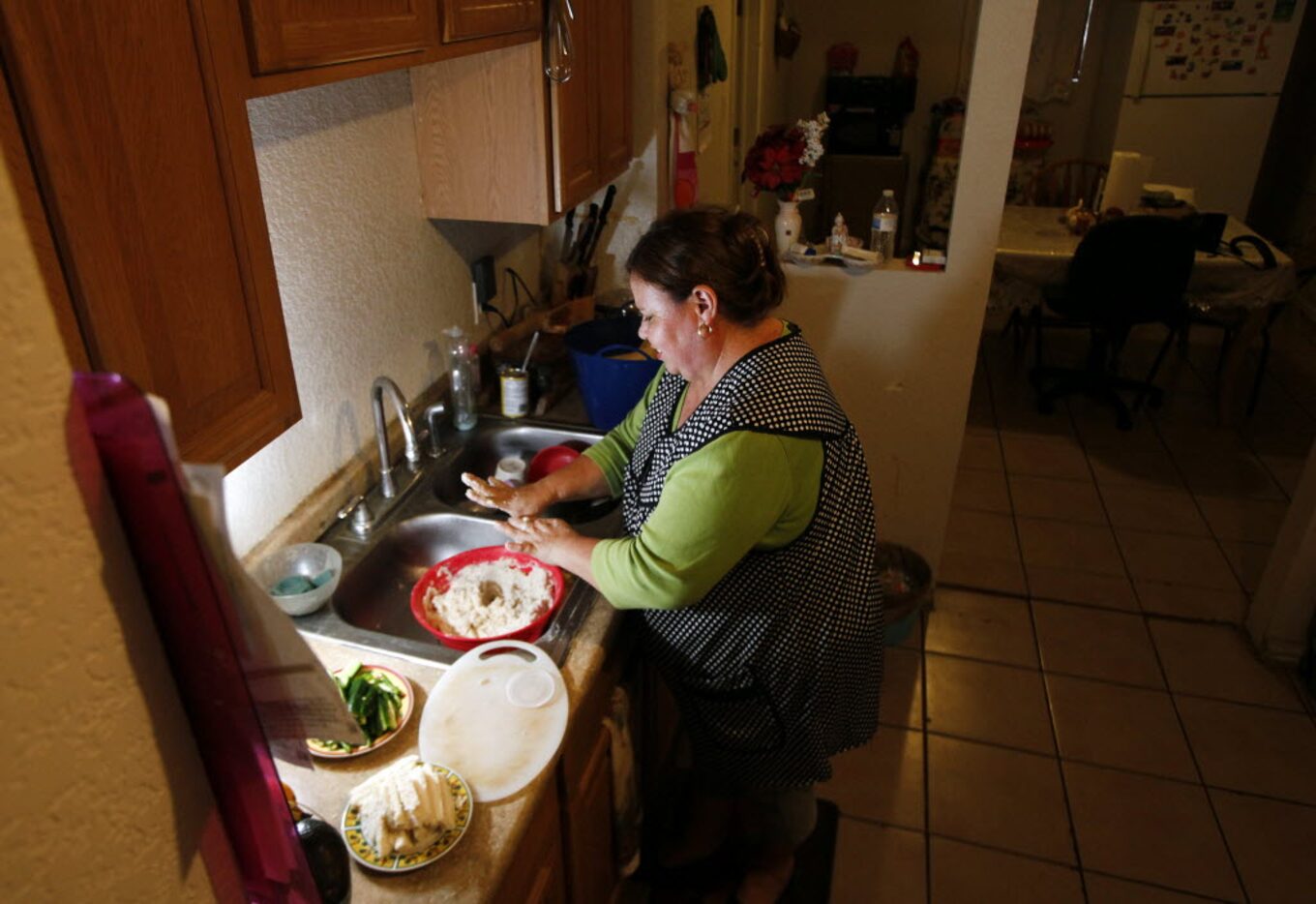 Mariela Diaz, 47, stirs and mixes a corn dough with her hands as she prepares to make...