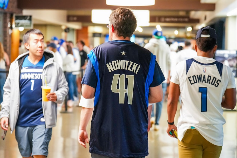 A Dallas Mavericks fan wears a Dirk Nowitzki jersey as he walks the concourse with Minnesota...