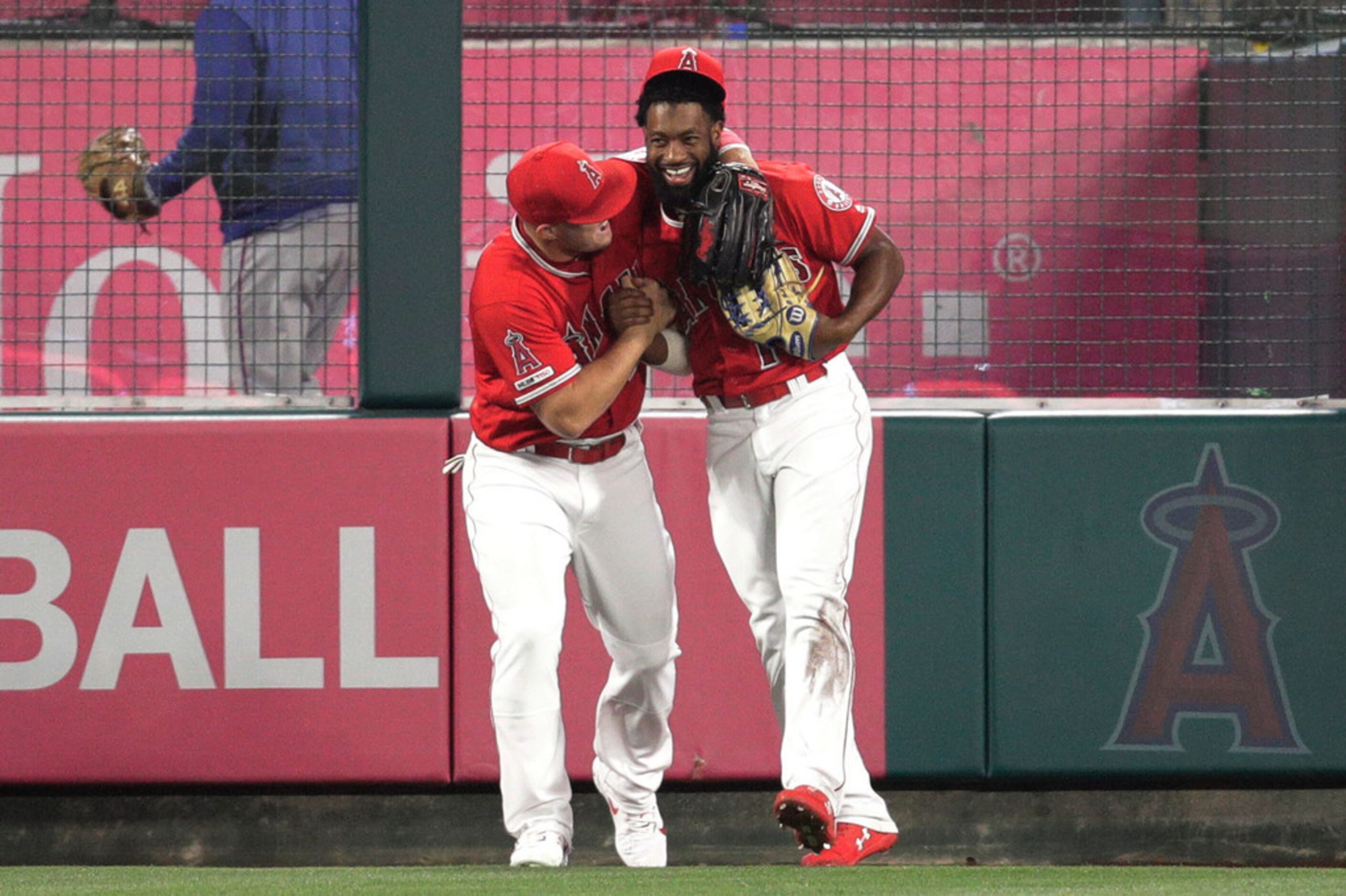 Los Angeles Angels' Brian Goodwin, right, is hugged by Mike Trout after catching a ball hit...