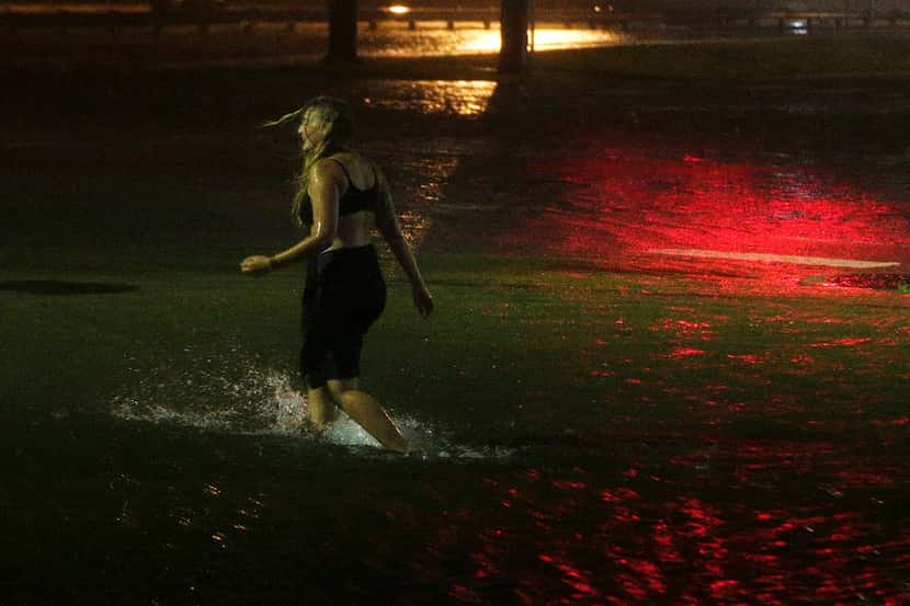 A woman wades through a flooded Water St. in downtown Mobile, Ala., during Hurricane Nate,...