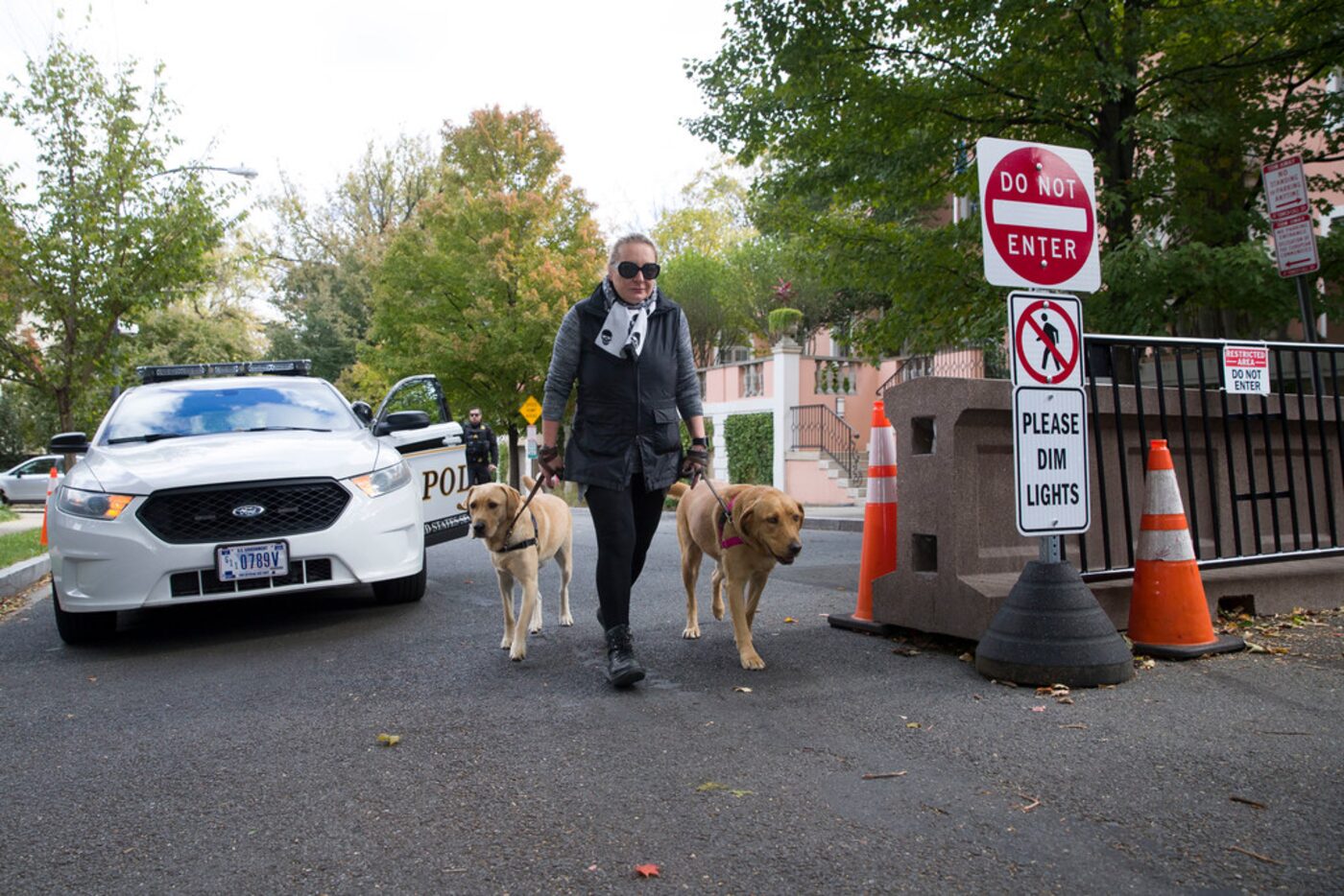 An officer with the Uniform Division of the Secret Service sits in his car as a woman walks...