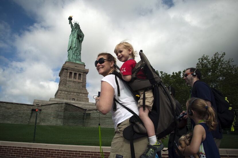 A family walks by the Statue of Liberty on the first day its reopening to the public on July...
