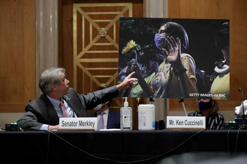 Sen. Jeff Merkley (D-OR) refers to a photo of peaceful protesters during a Senate Judiciary...