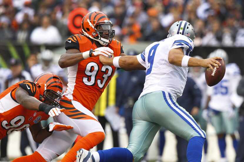 Dallas Cowboys quarterback Tony Romo (9) stiff arms Cincinnati Bengals defensive end Michael...