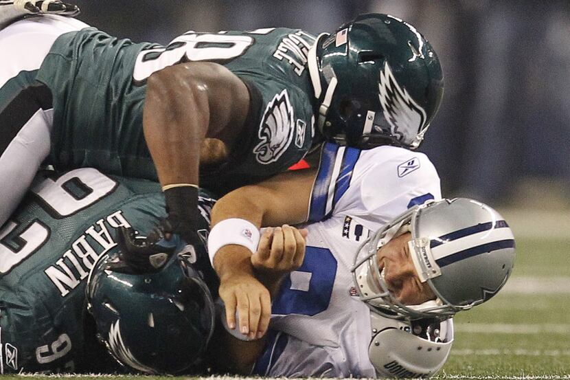 Dallas Cowboys quarterback Tony Romo (9) is taken to the turf by Philadelphia Eagles...