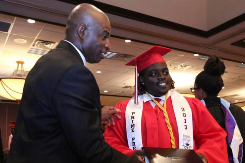 
Prime Prep co-founder Deion Sanders helps Devonte Elder with his diploma at the end of the...