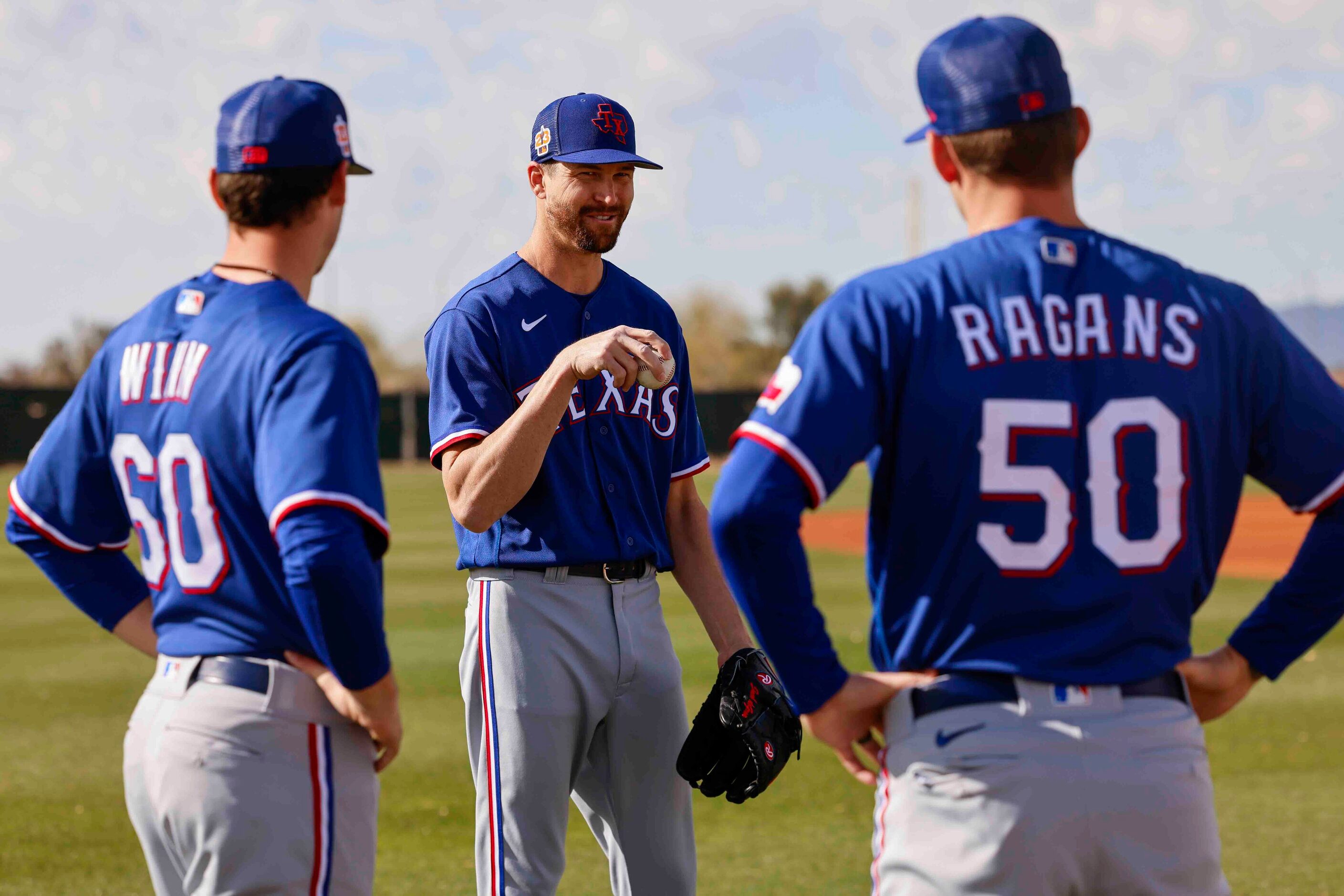 Texas Rangers pitchers Cole Winn, left, and Cole Ragans, right, listens to pitcher Jacob...