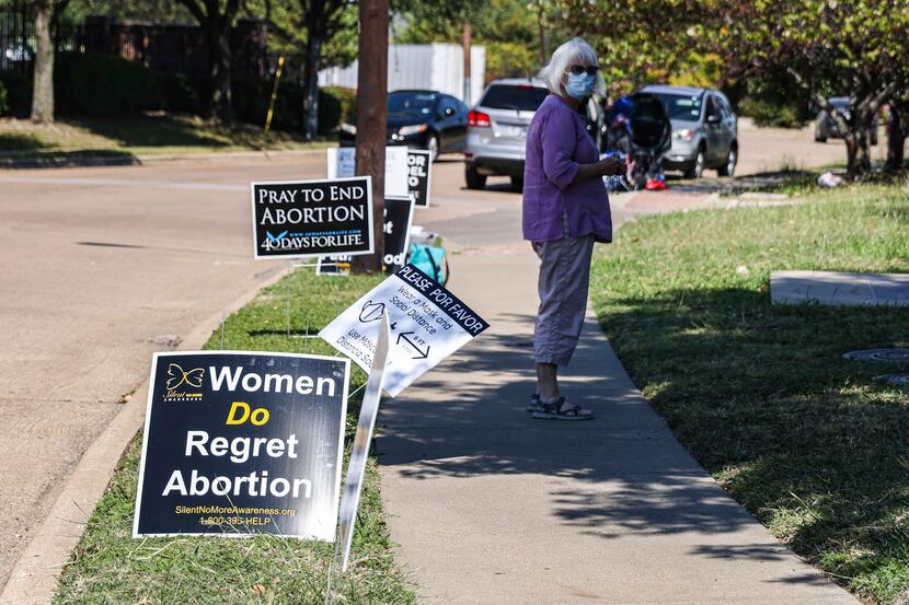 A protester stands on the sidewalk near Planned Parenthood next to anti-abortion signs in...