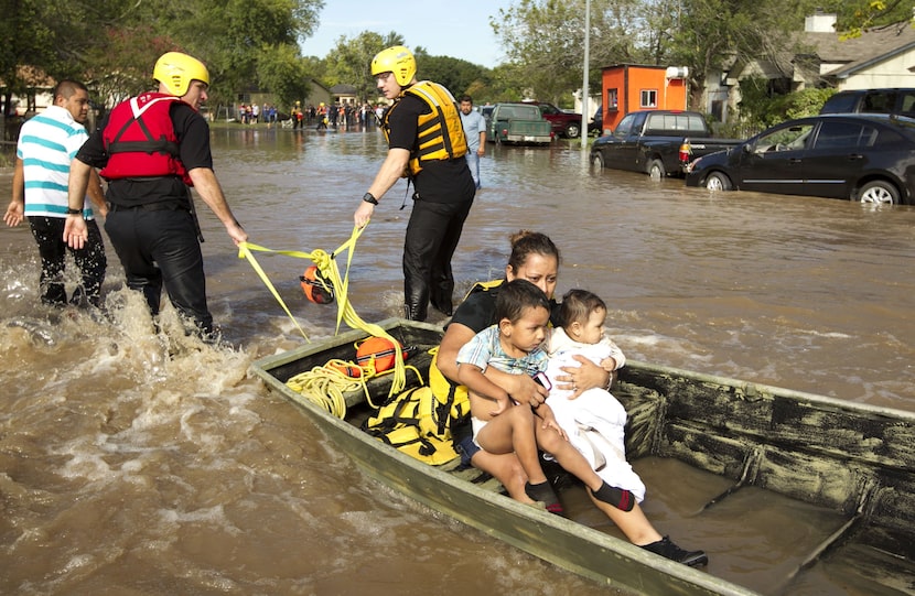 Isabel Rodriguez and her children Christopher, left, 3, and Rubi, 8 months, are carried on a...