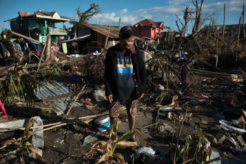 A man walks home with his son Monday after Friday's devastating typhoon in the central...