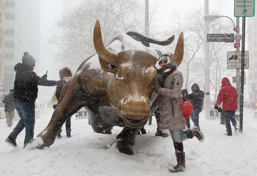 NEW YORK, NY: A woman poses for photos with the "Charging Bull" statue in Manhattan's...