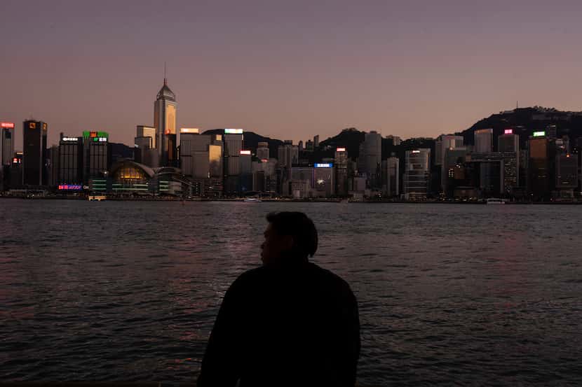 A visitor sits along a promenade next to Victoria Harbour in Hong Kong, Tuesday, March 12,...