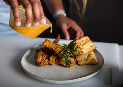 In this early 2020 photo, Tiffany Derry drips Roots Chicken Shak sauce over fried chicken....