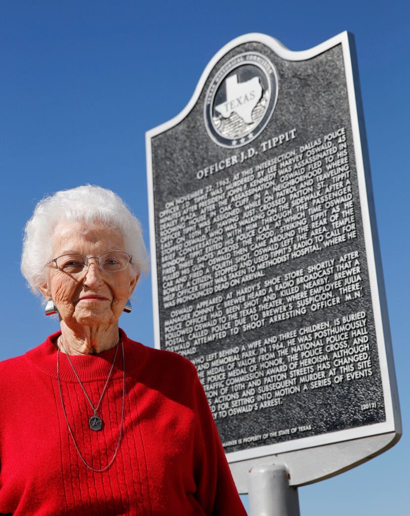Marie Tippit poses for a photo next to a plaque dedicated to her husband near the...