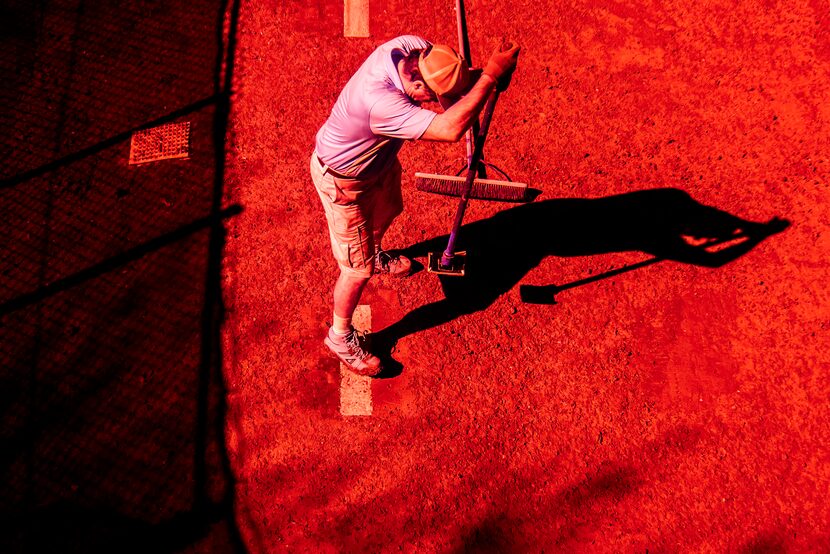 A groundskeeper prepares a bullpen before a spring training baseball game between the...